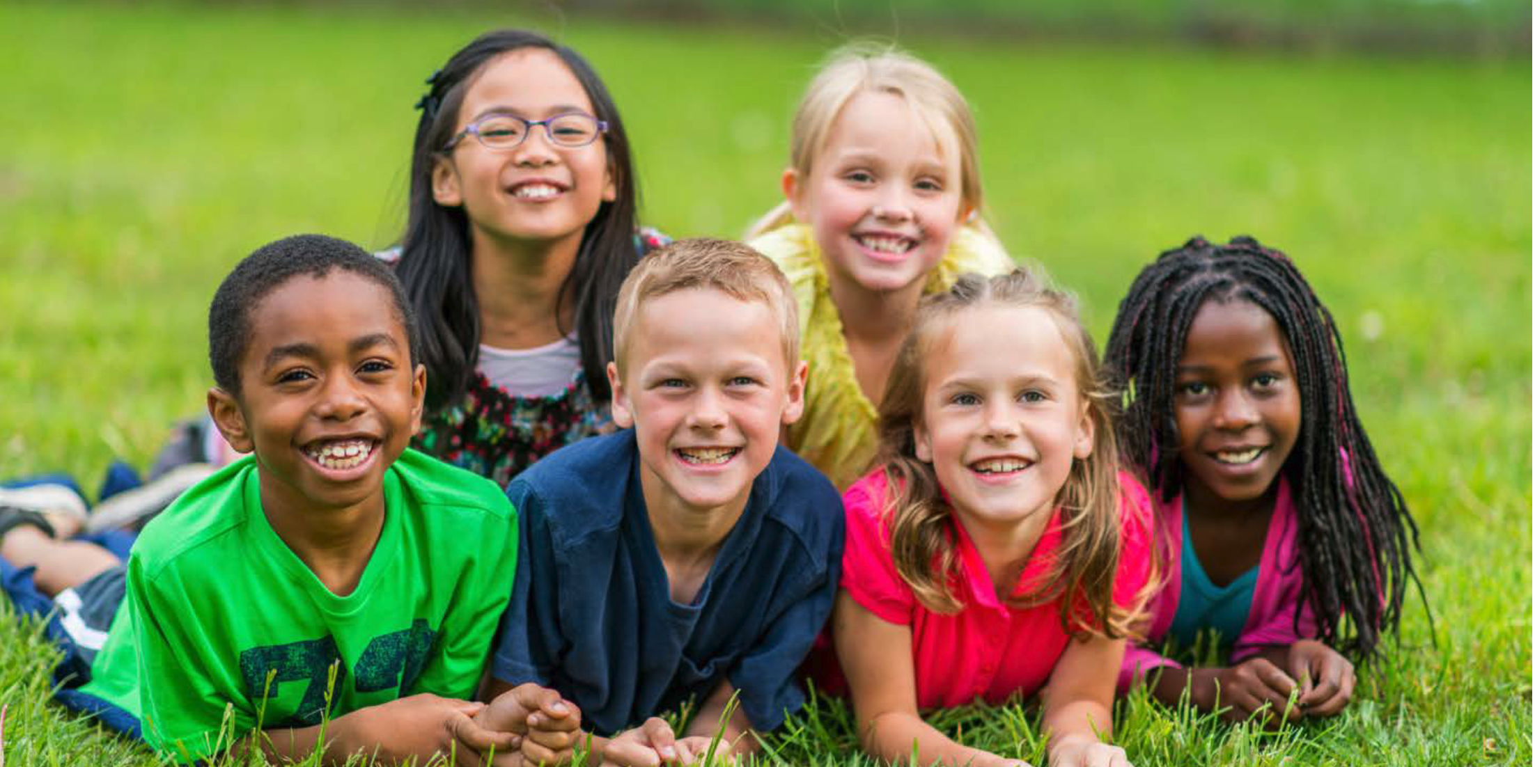 group of smiling children laying on the grass